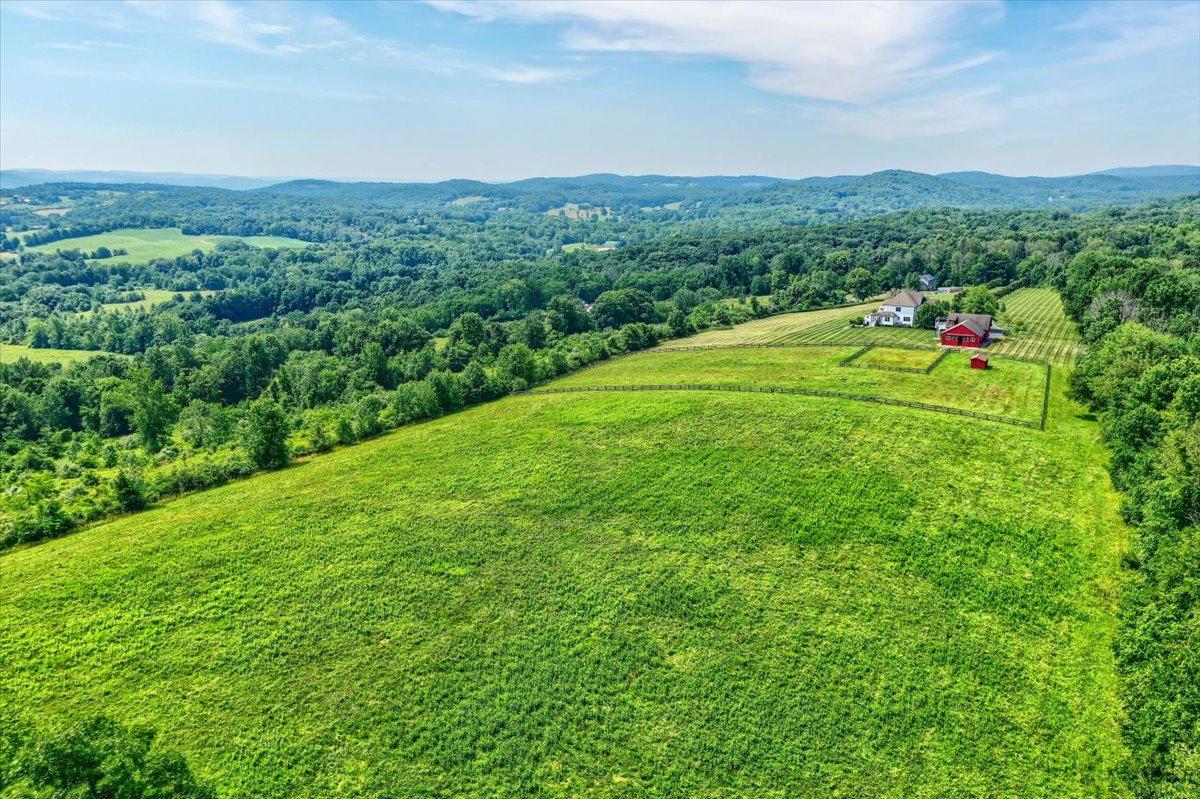 Aerial view of The Westtown Reset — private 23-acre estate, white farmhouse, red barn, Hudson Valley