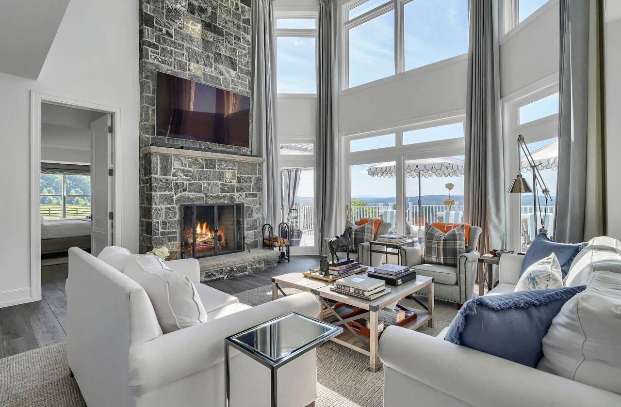 Grand living room at The Westtown Reset with floor-to-ceiling windows, stone fireplace, and Hudson Valley views — private estate upstate New York