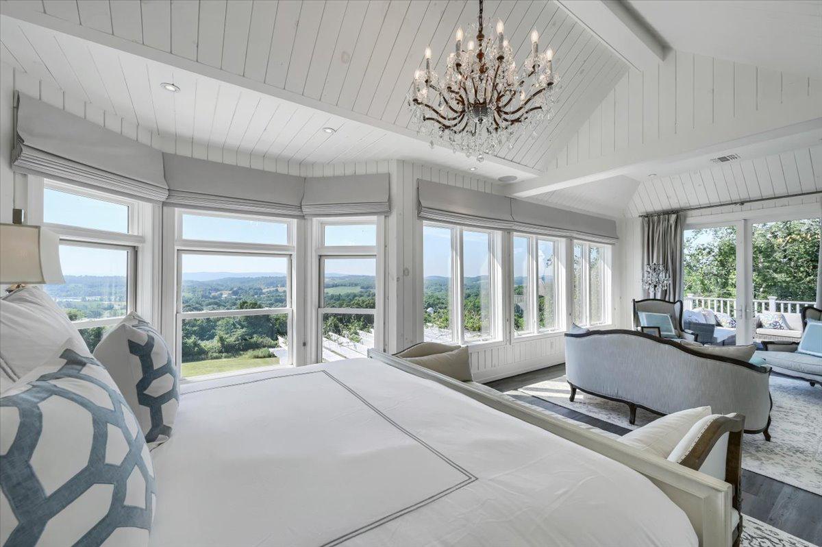 Primary bedroom at The Westtown Reset — king bed, chandelier, Hudson Valley views, private balcony