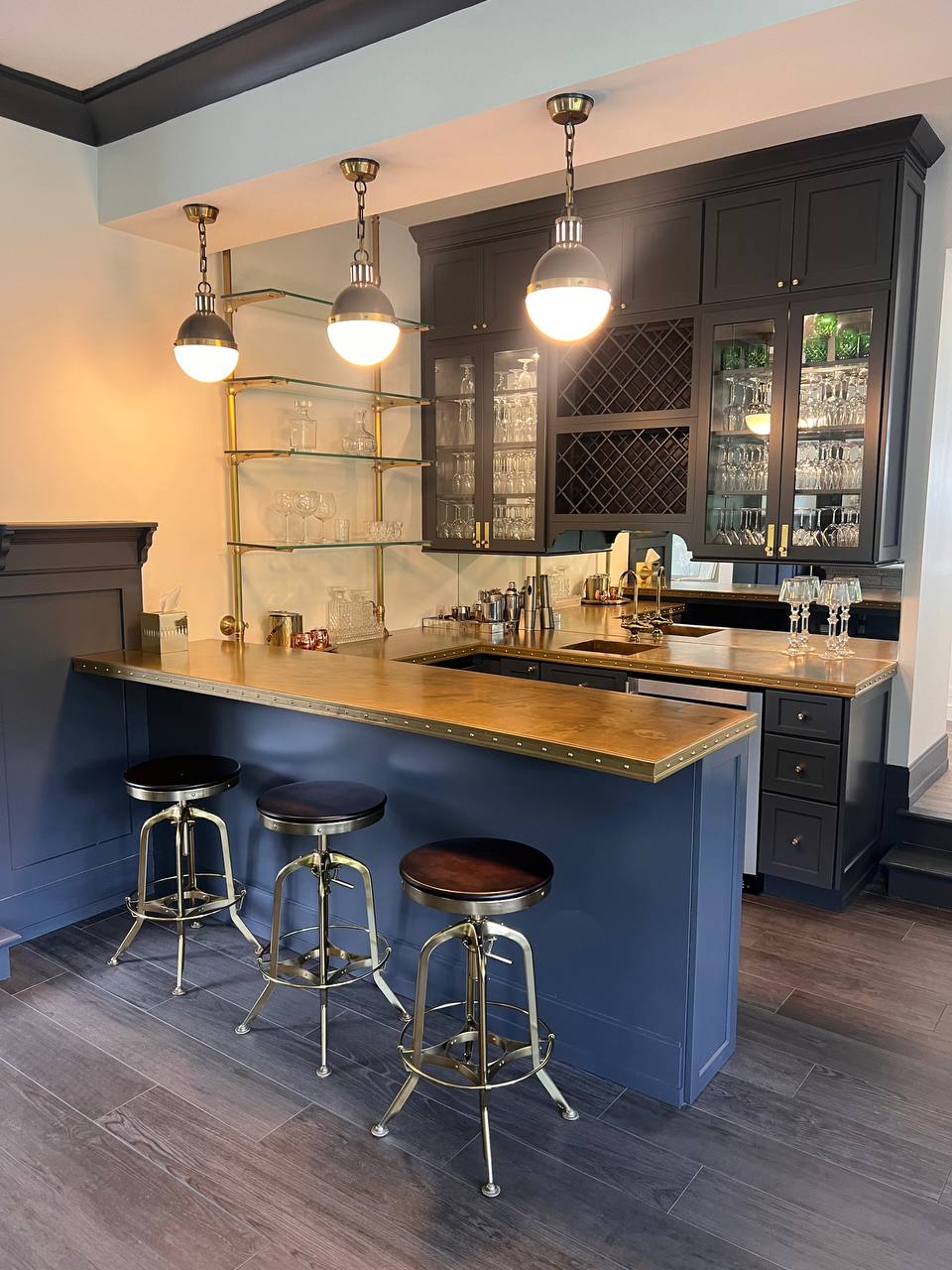 Private speakeasy-style bar at The Westtown Reset — navy cabinets, brass pendants, copper bar top, wine storage — private estate upstate New York