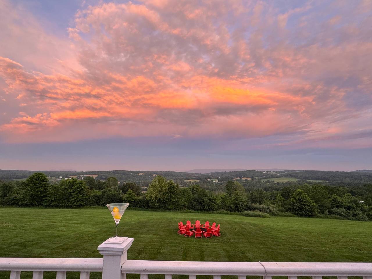 Sunset view from the deck at The Westtown Reset with fire pit circle and red Adirondack chairs overlooking the Hudson Valley — private estate upstate NY